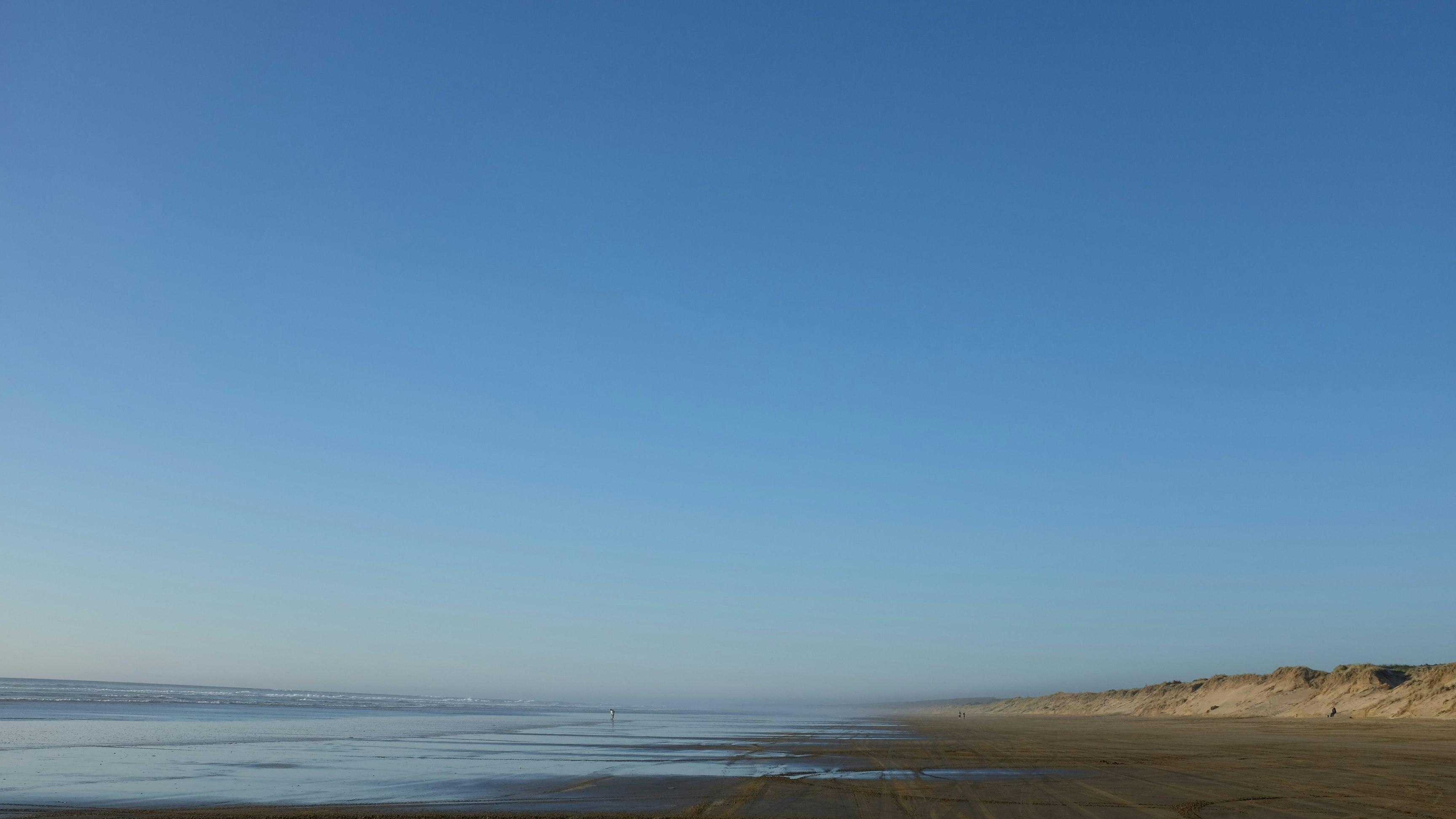 body of water and gray seashore under blue sky